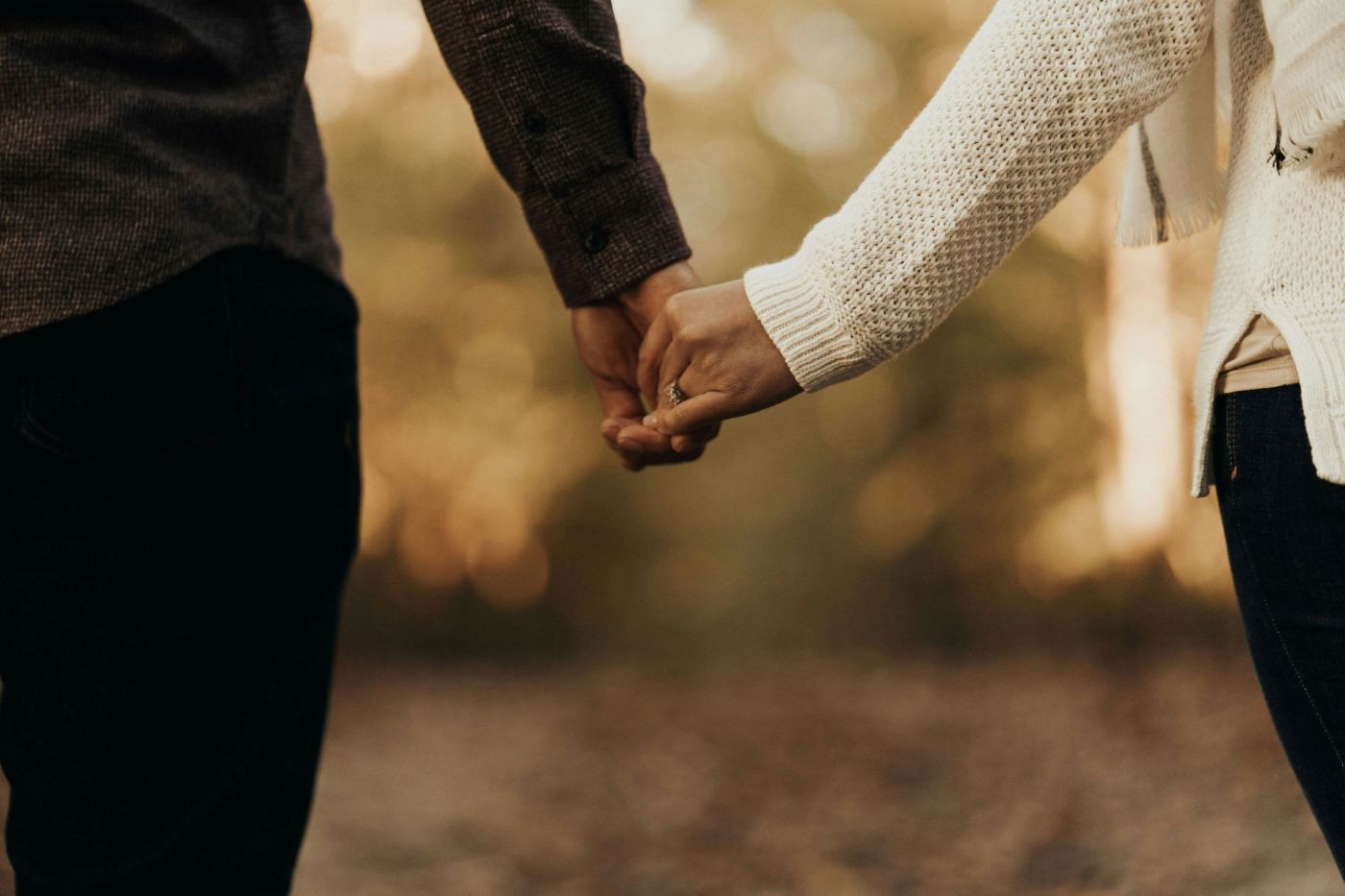 A man and a woman are holding hands while sitting on a couch.