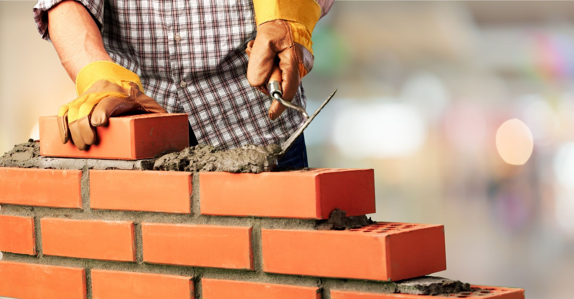 A man is building a brick wall with bricks and cement.
