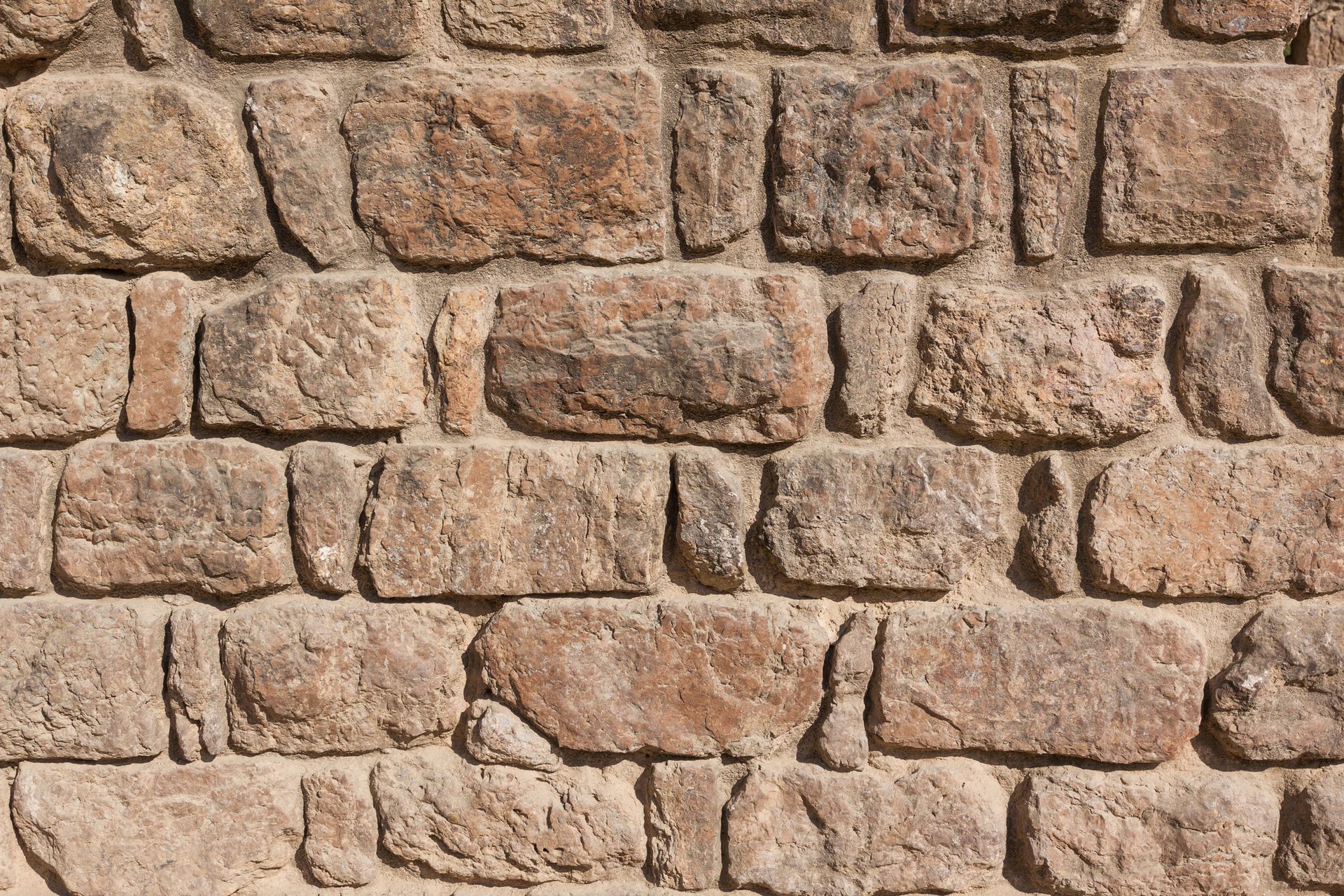 A man is applying mortar to a brick chimney.