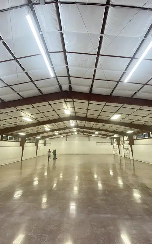 A large empty warehouse with a shiny concrete floor and ceiling.