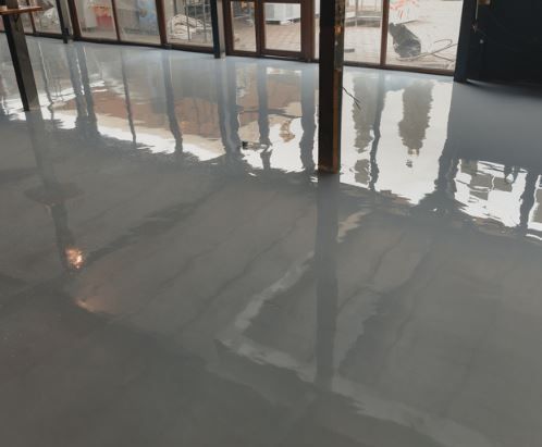 A shiny concrete floor in a room with a lot of windows.