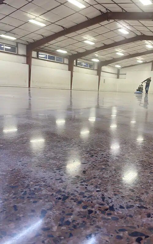 A man is standing on a shiny concrete floor in a large building.