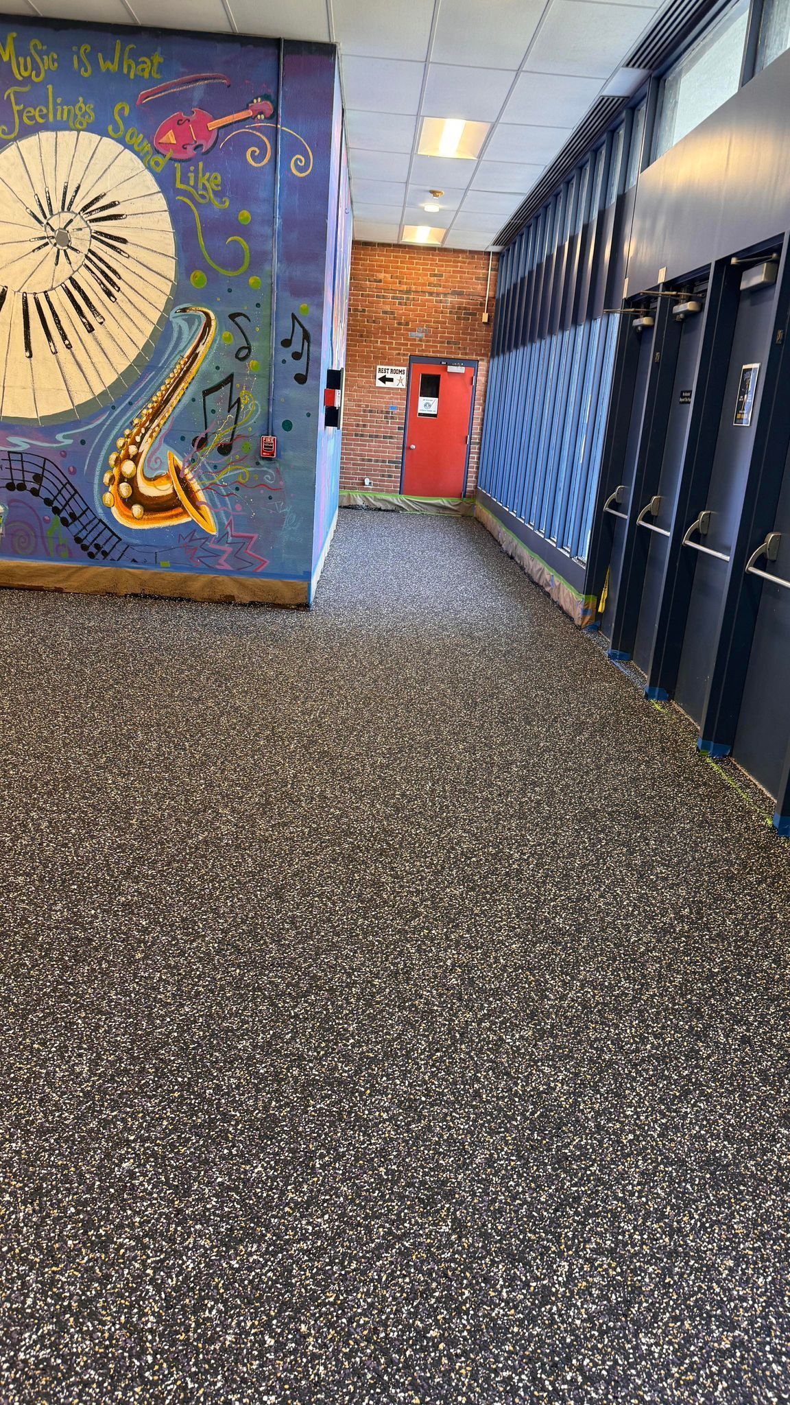 A hallway with a mural on the wall and a saxophone on the floor.