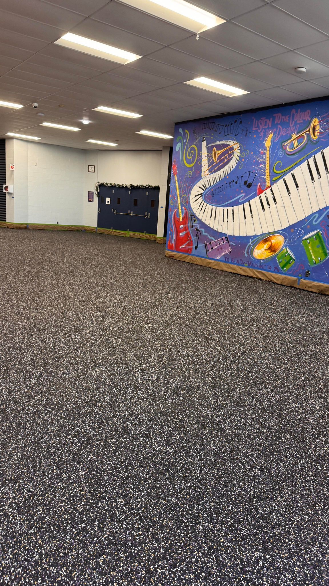 A large empty room with a painting of a piano on the wall.