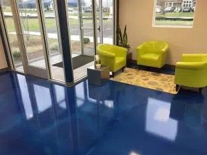 A waiting room with blue floors and yellow chairs.