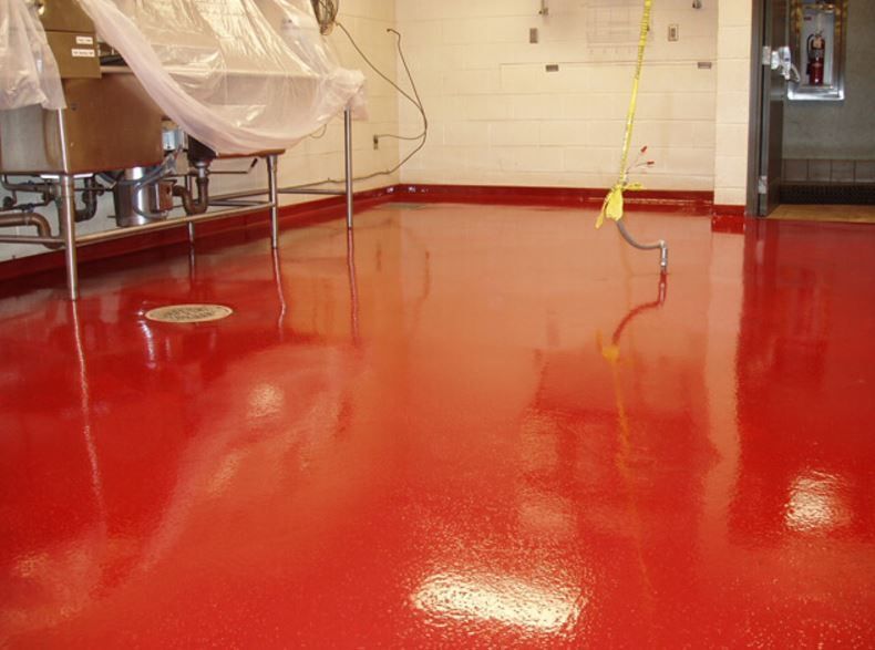 A kitchen with a red floor and a yellow mop