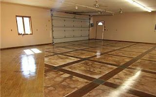 A large empty garage with a stained concrete floor and a garage door.