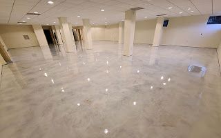 A large empty room with a marble floor and columns.