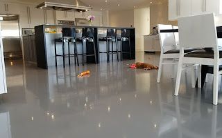 A dog is laying on the floor in a kitchen next to a table and chairs.