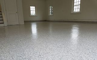 A large empty room with a white floor and windows.
