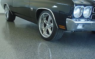 A black car is parked in a garage with a shiny floor.