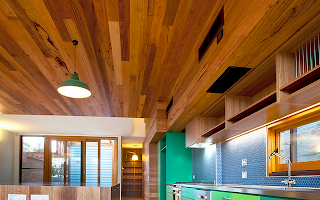 A kitchen with a wooden ceiling and green cabinets.