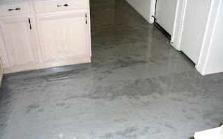 A kitchen with a concrete floor and white cabinets.