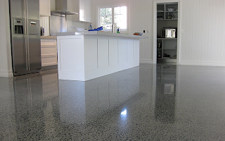 A kitchen with a shiny concrete floor and white cabinets.