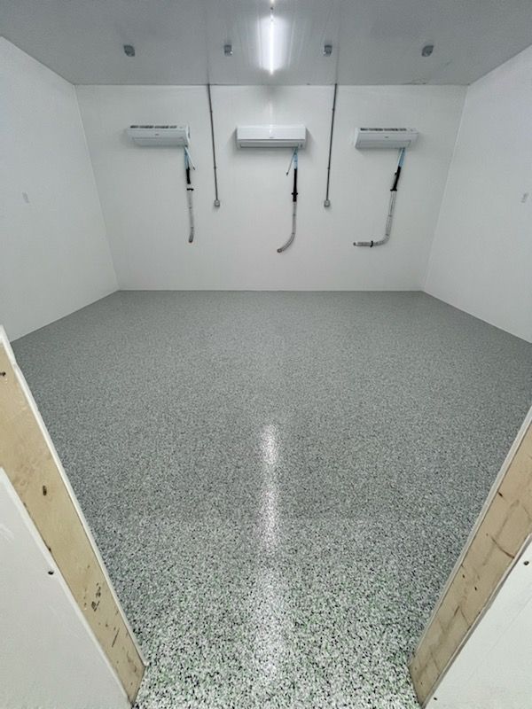 An empty room with a gray floor and white walls