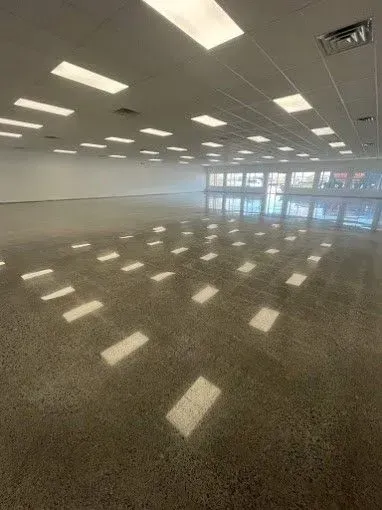 A large empty room with a lot of windows and lights on the ceiling.