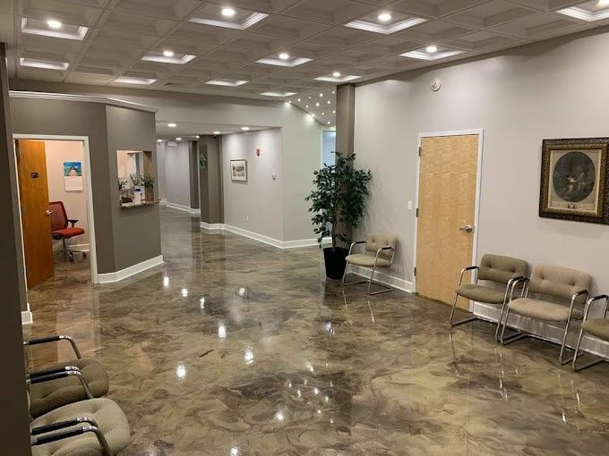 A waiting room with chairs and a plant in a large room.