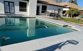 A large swimming pool is in the backyard of a house.