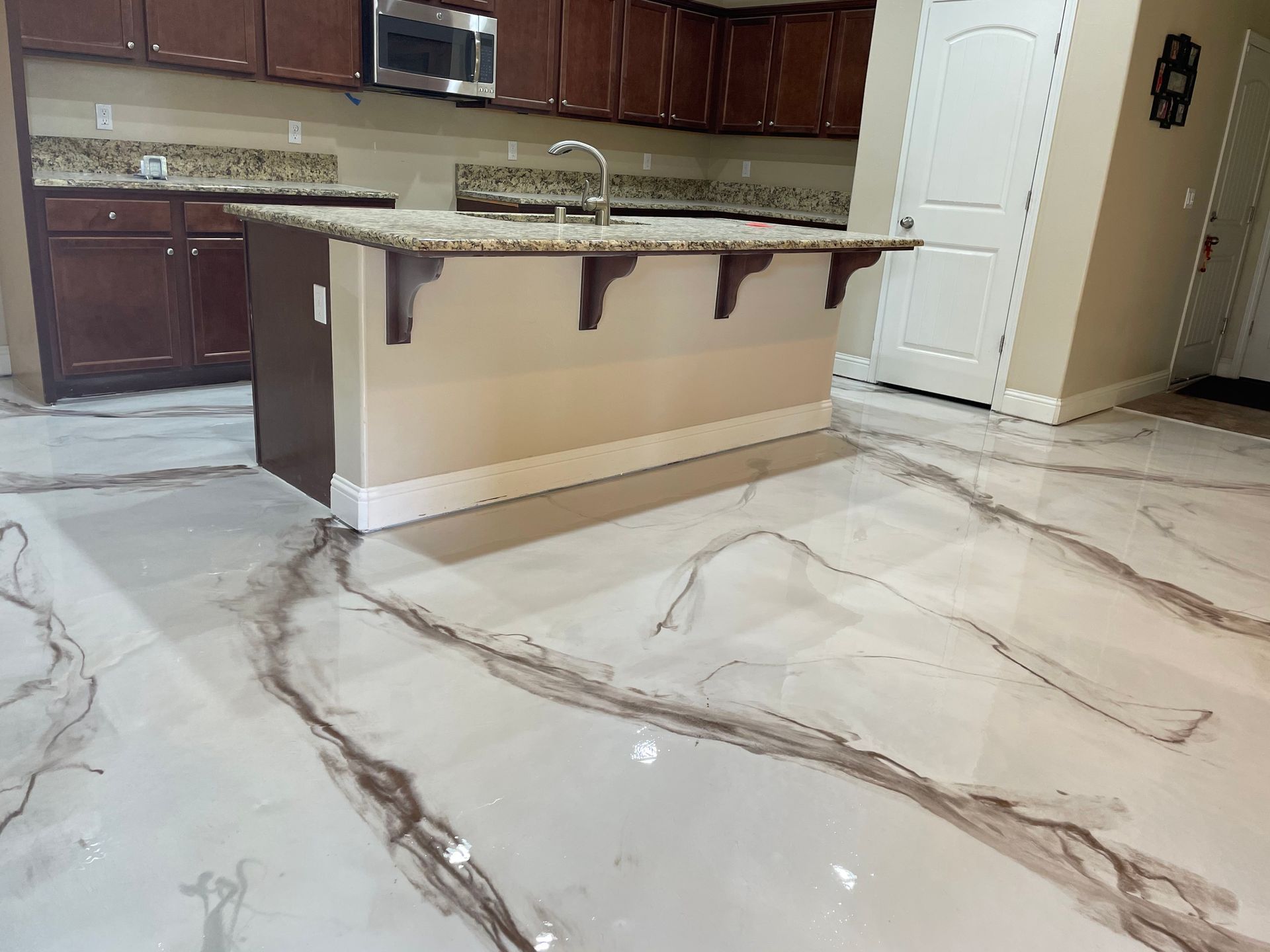 A kitchen with a large island and a marble floor.