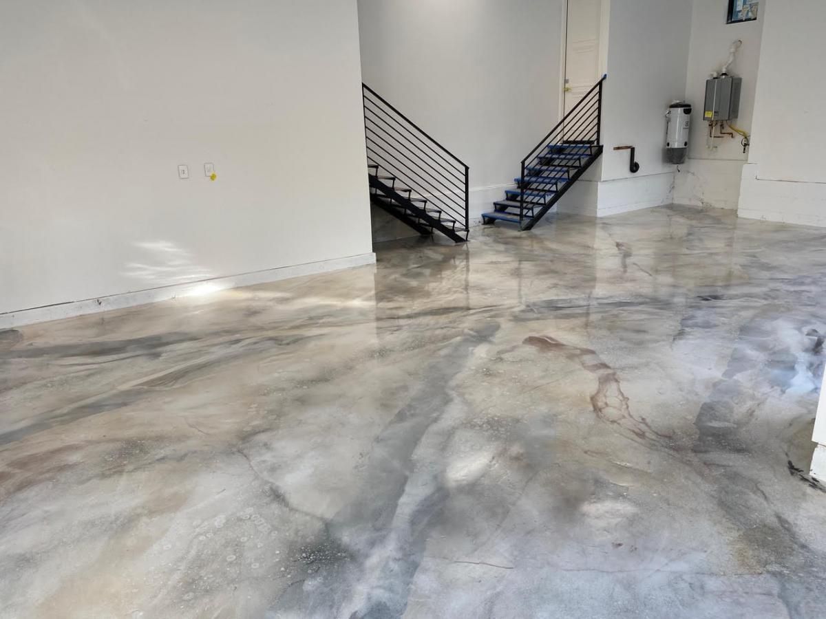 A room with a staircase and a shiny concrete floor.