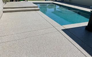 A swimming pool with a concrete deck and steps leading to it.