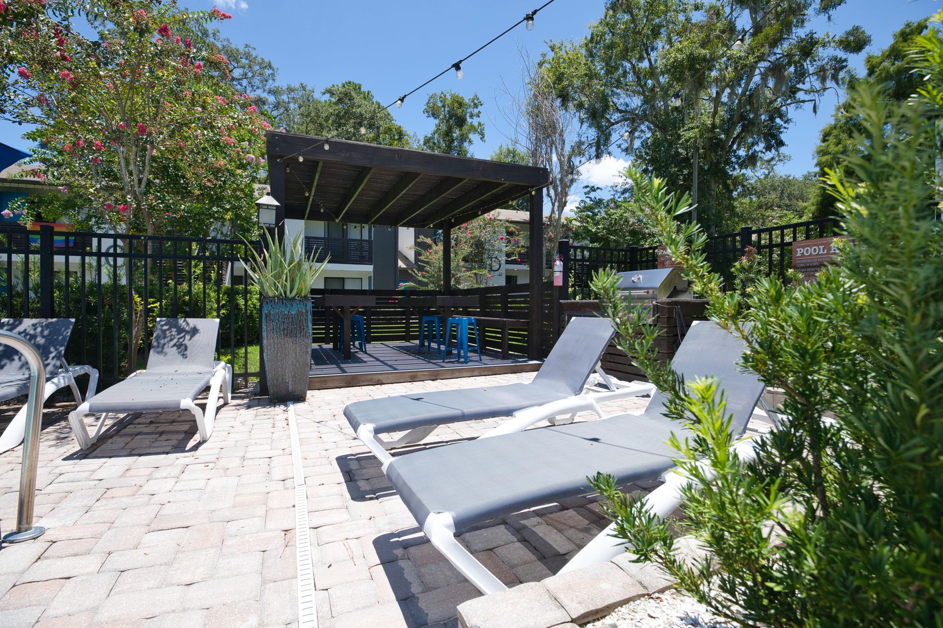 A patio with lounge chairs and a gazebo in the background