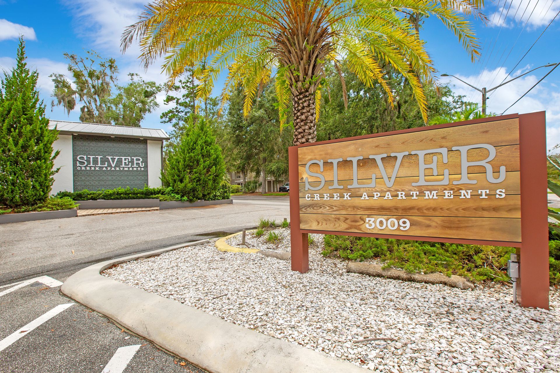 A sign for silver apartments is in front of a palm tree