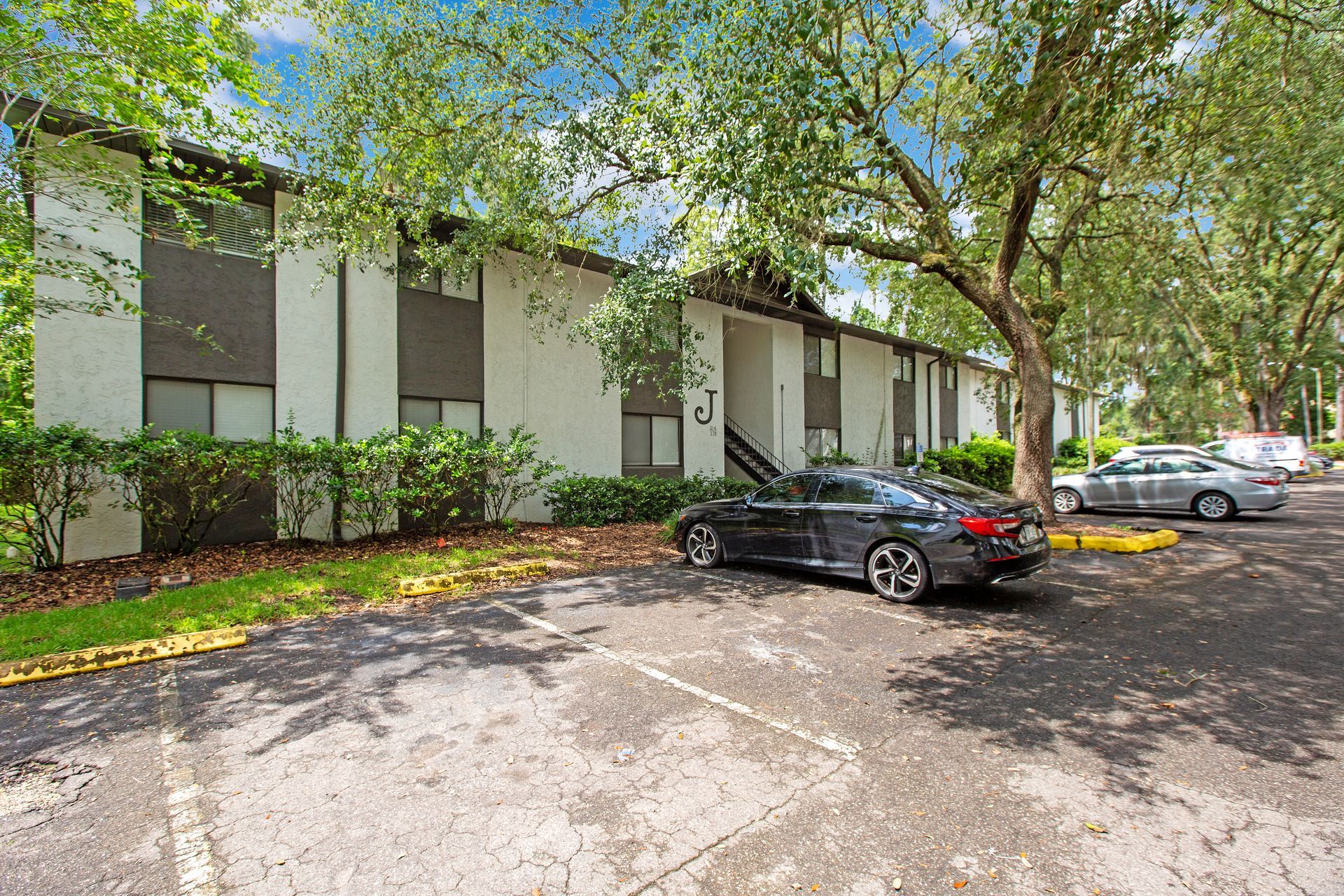 A black car is parked in front of a large apartment building.