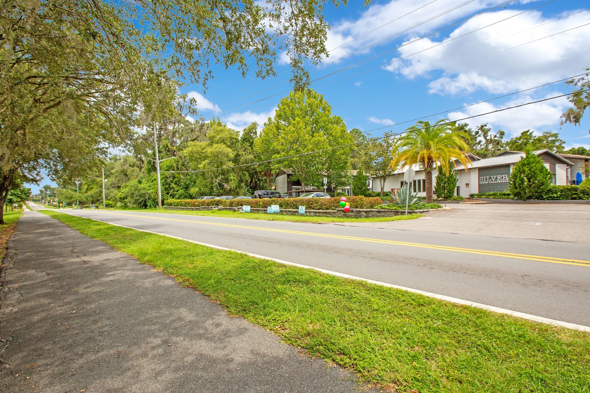 A sidewalk along the side of a road with a house in the background.