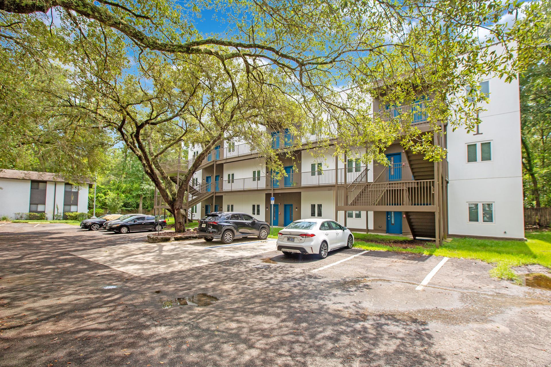 A white apartment building with cars parked in front of it.