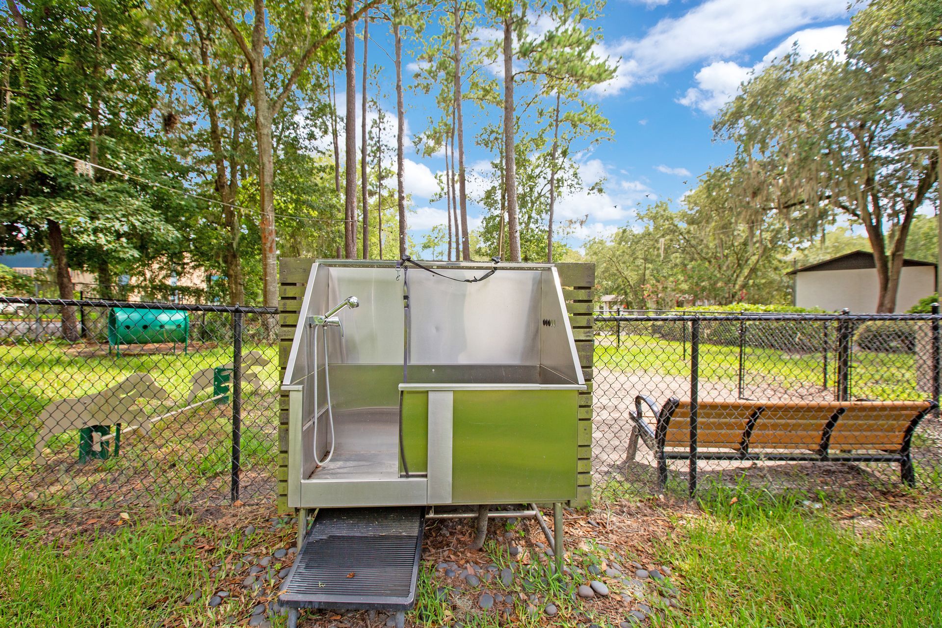 A dog bathtub is sitting in the grass next to a bench.