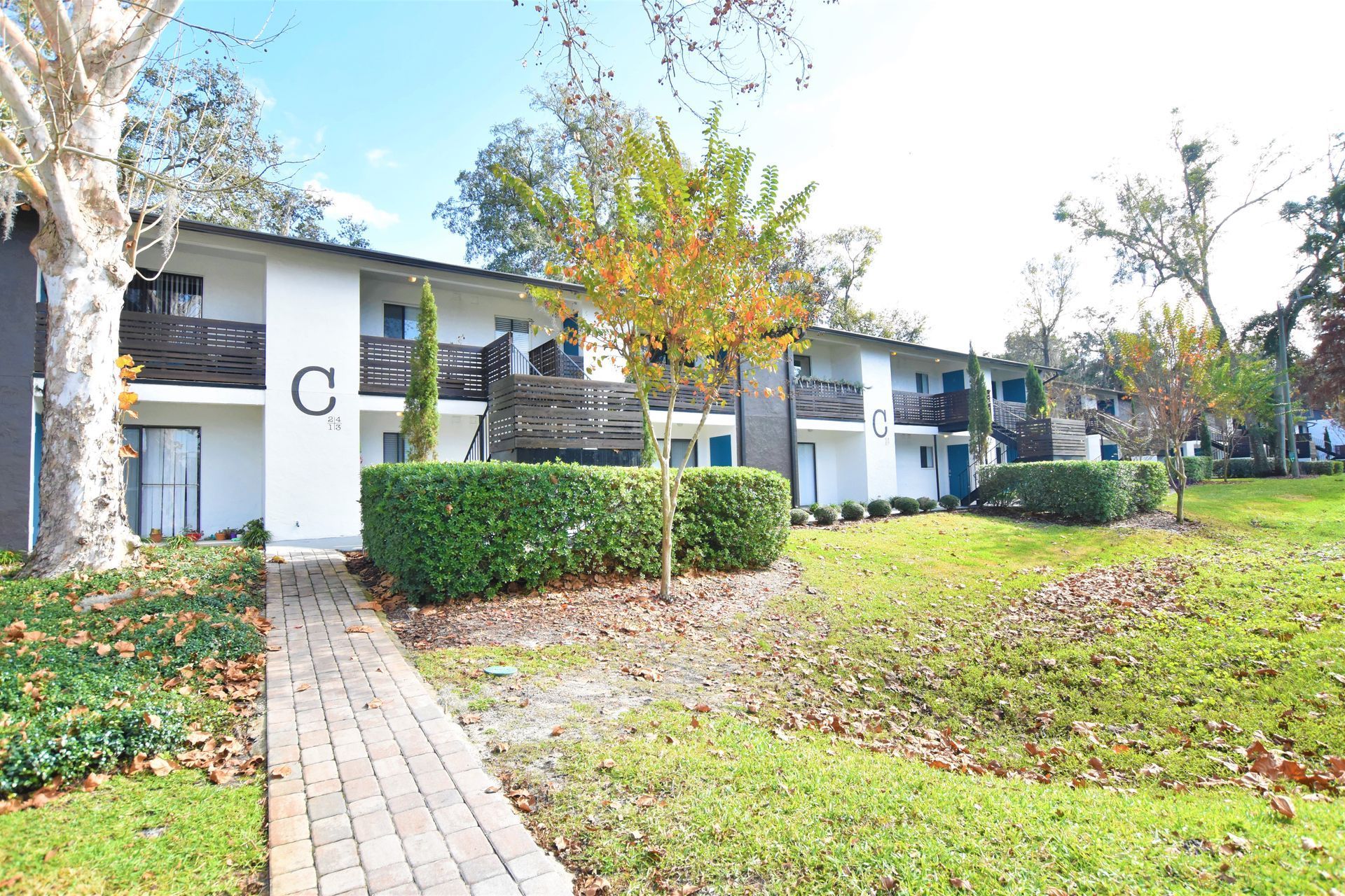 A white apartment building with a brick walkway leading to it.