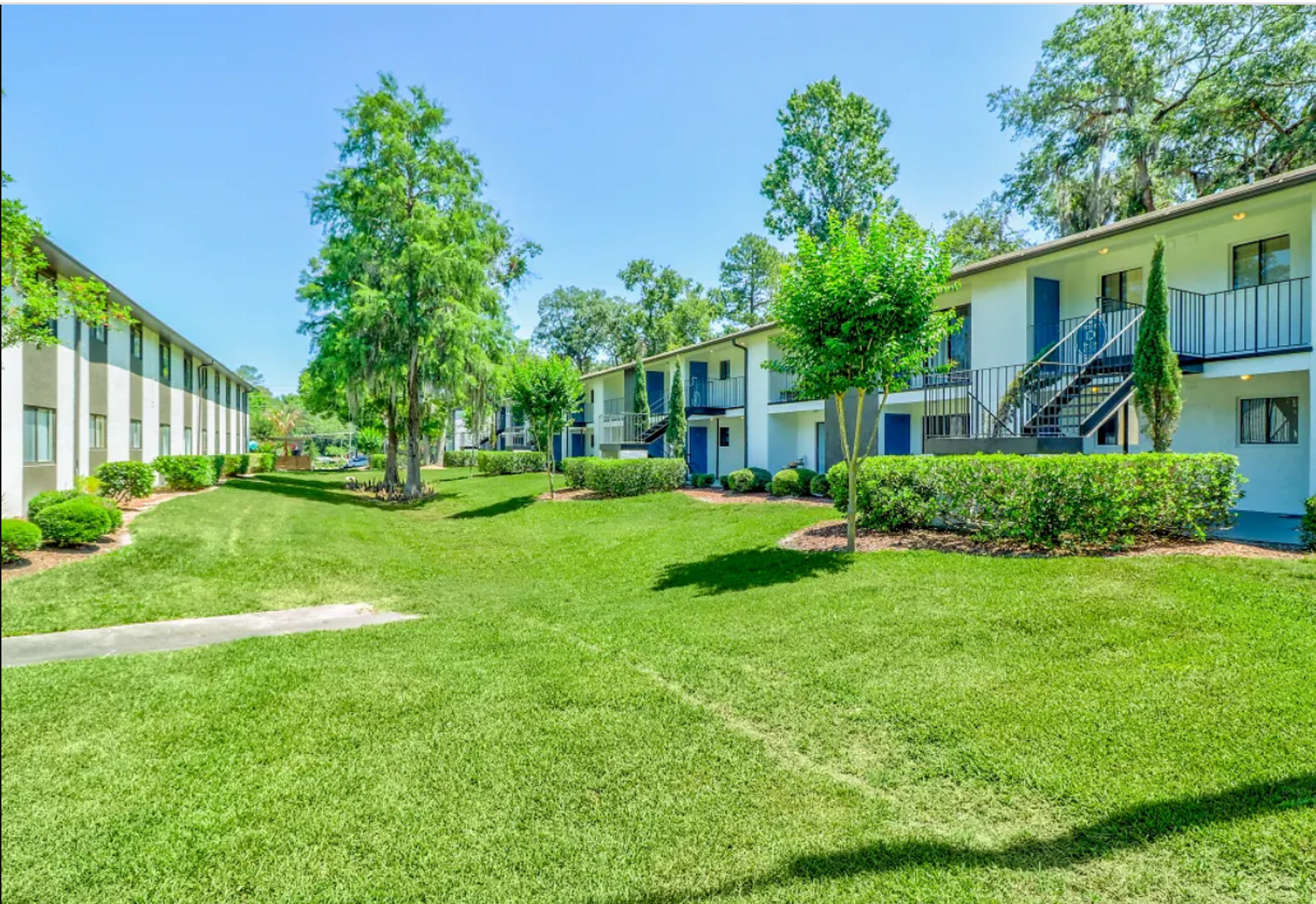 A row of apartment buildings with a lush green lawn in front of them.