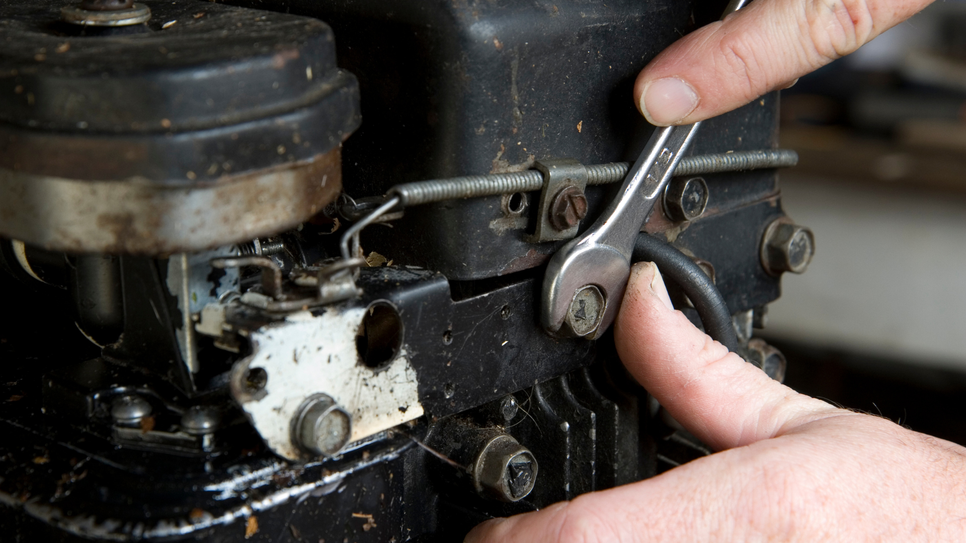 A person is working on a machine with a wrench.