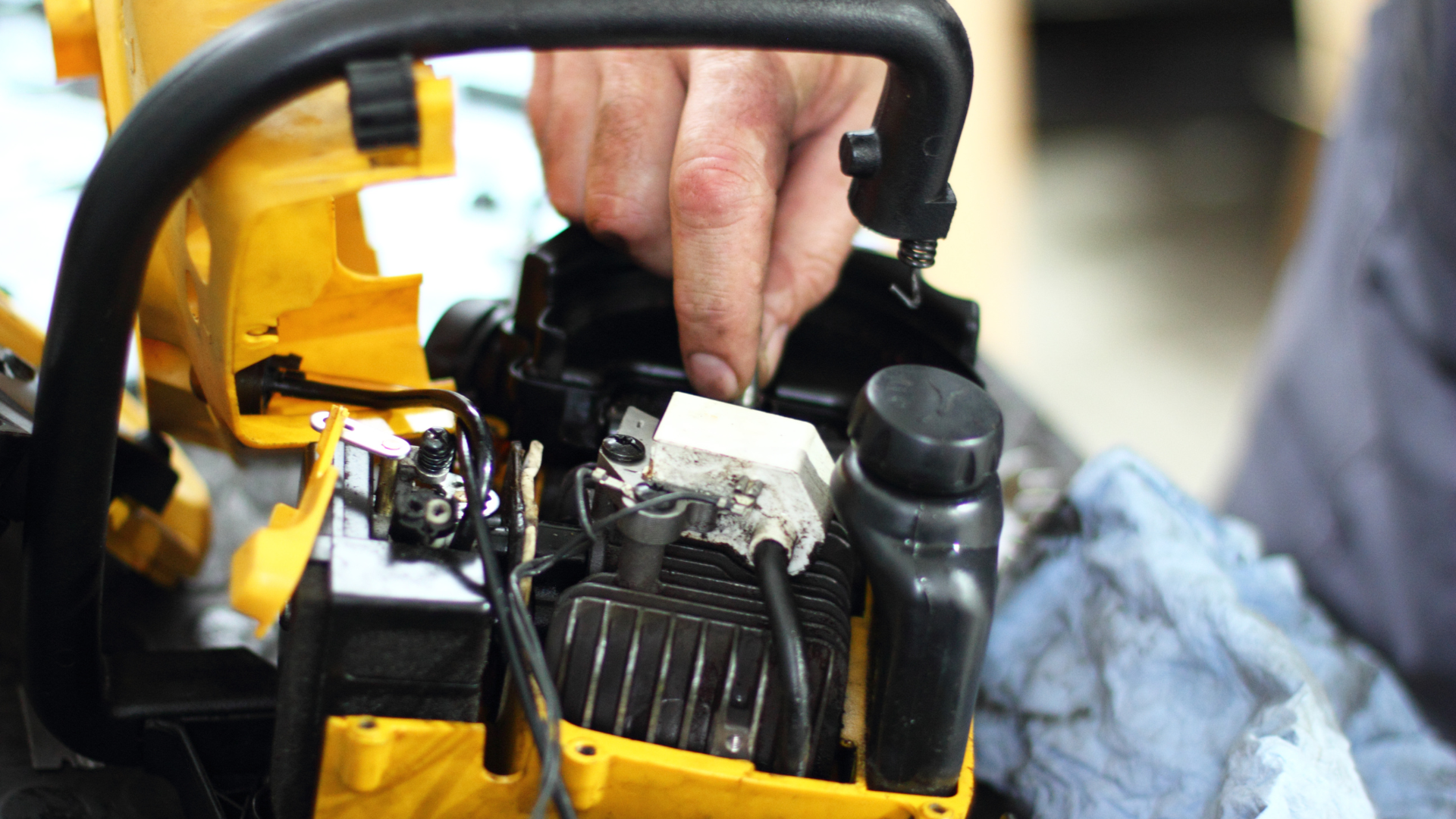 A person is working on a chainsaw in a garage.