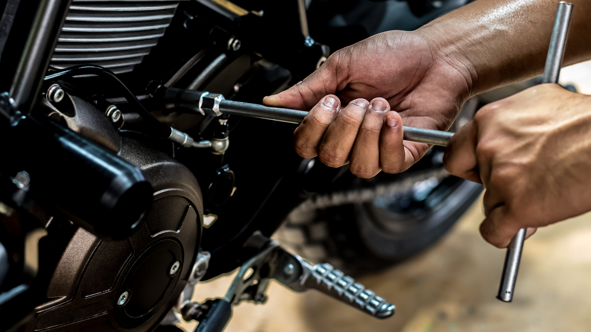 A person is working on a motorcycle with a wrench.