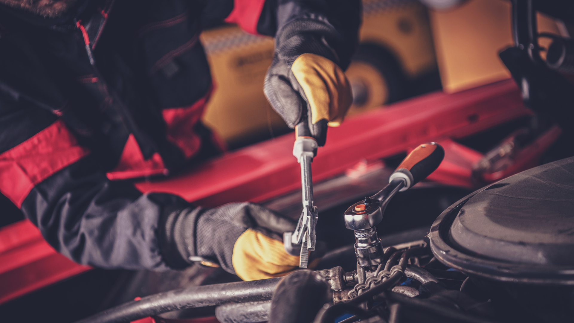 A man is working on a car engine with a wrench.