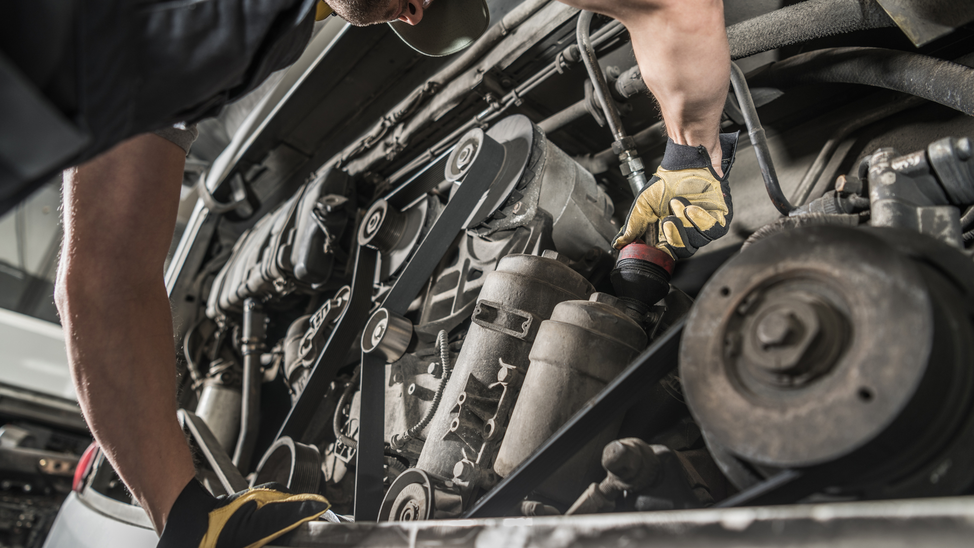 A man is working on the engine of a truck.