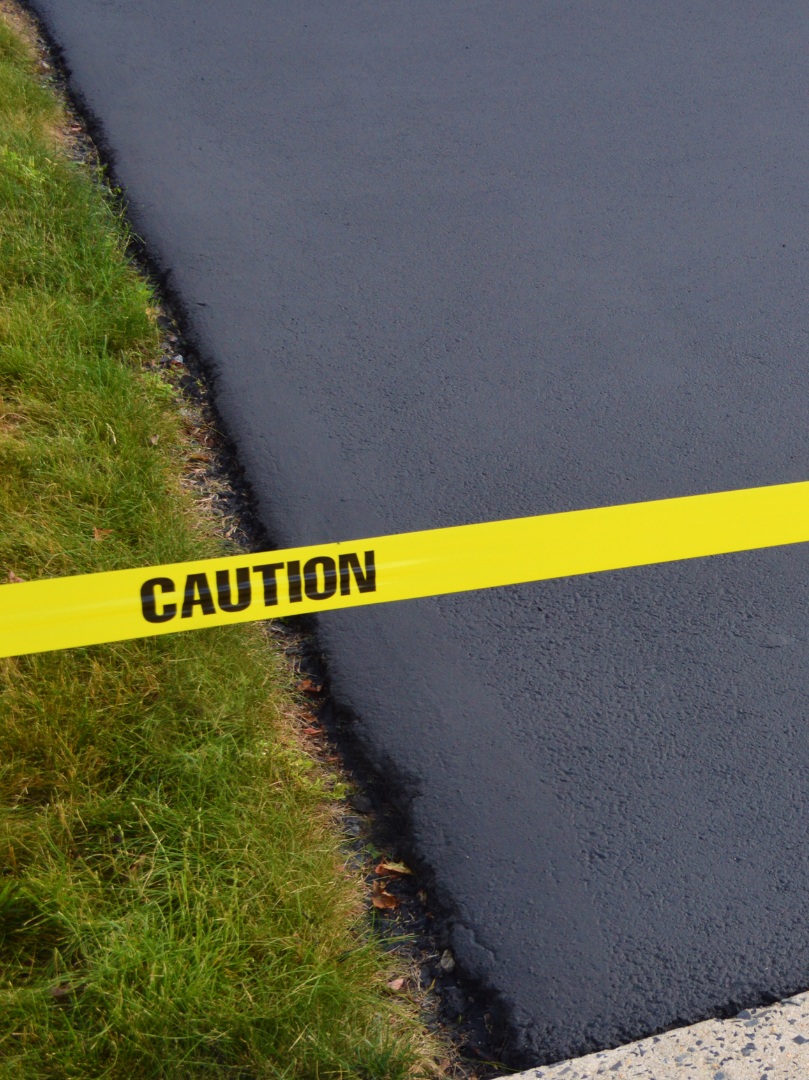 A yellow caution tape is laying on the side of a road.