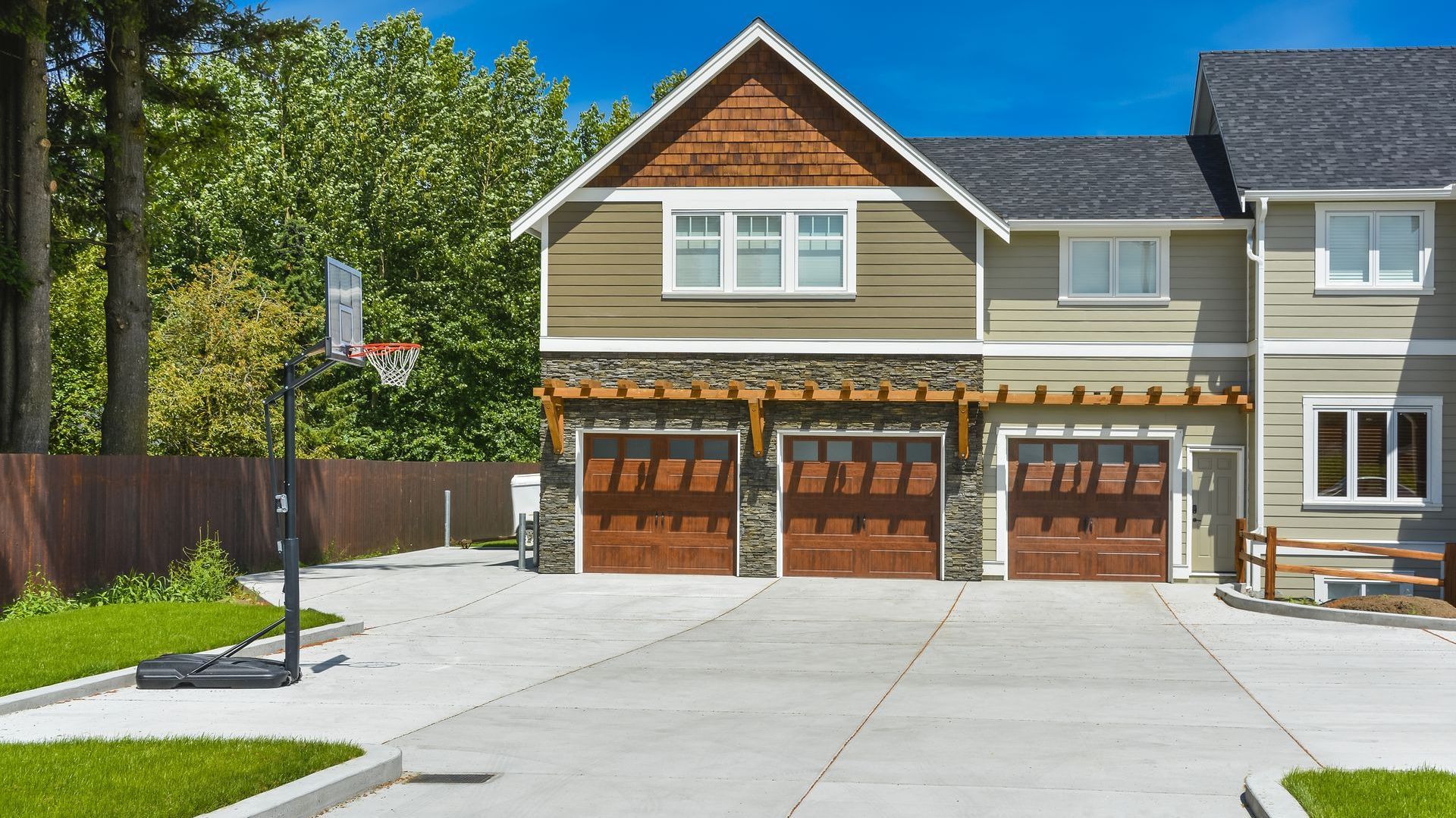 A house with two garage doors and a basketball hoop in front of it.