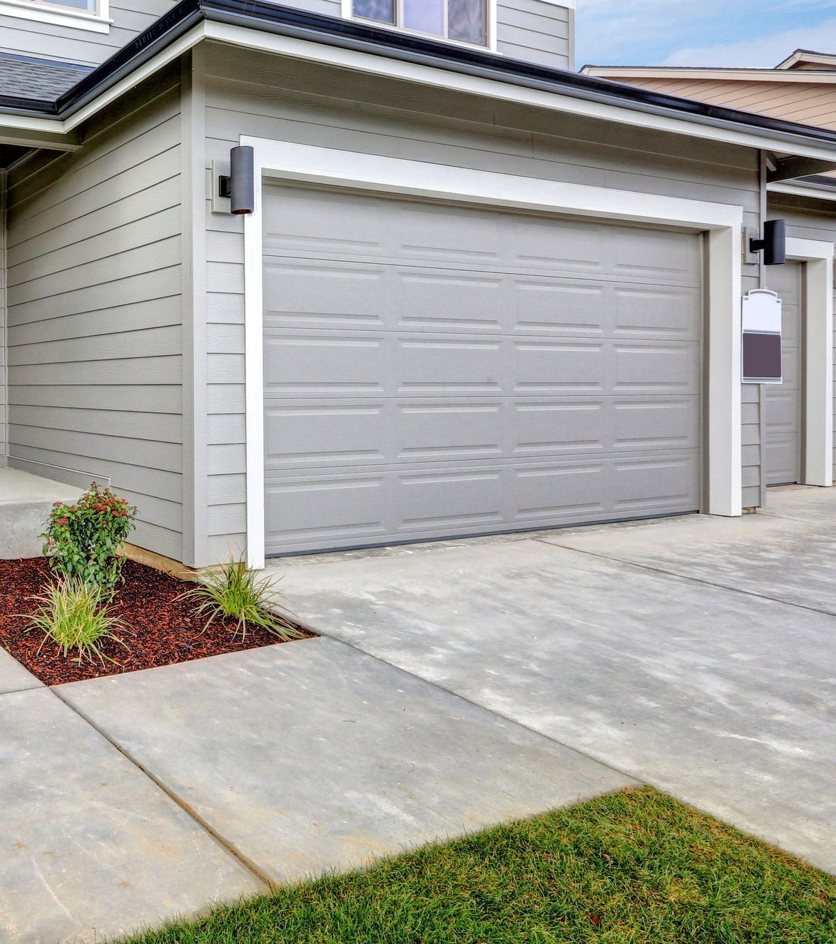 A house with two garage doors and a concrete driveway