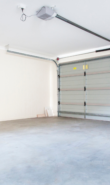 An empty garage with a garage door open and a garage door opener.