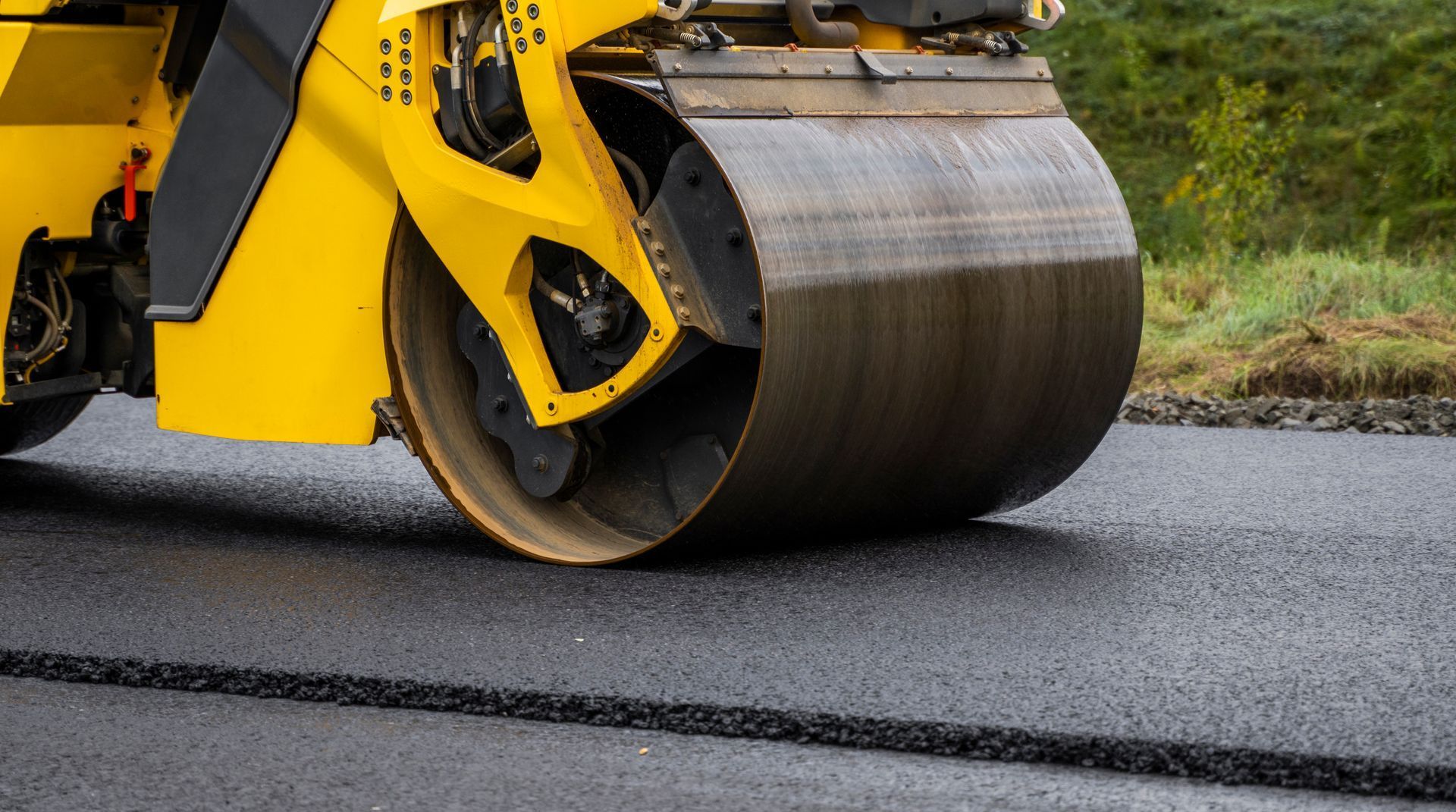 A yellow roller is rolling asphalt on a road.