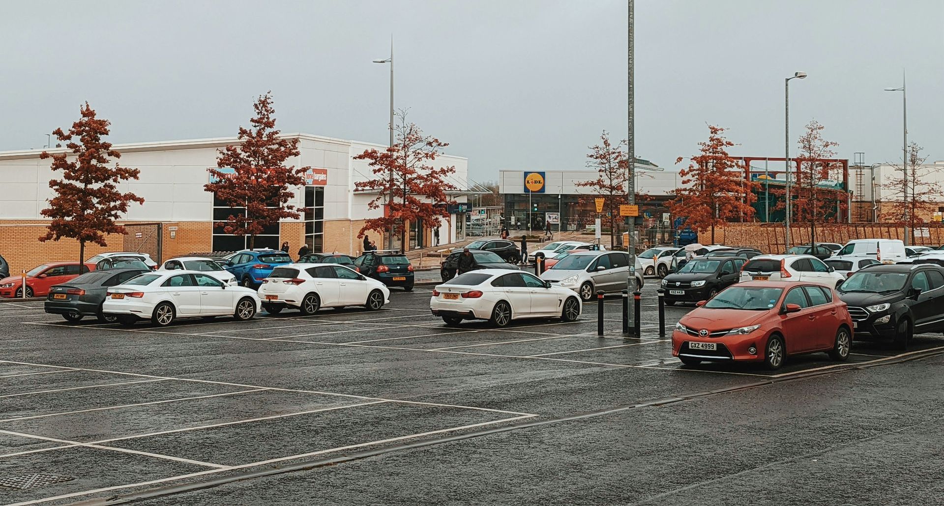 A lot of cars are parked in a parking lot in front of a building.