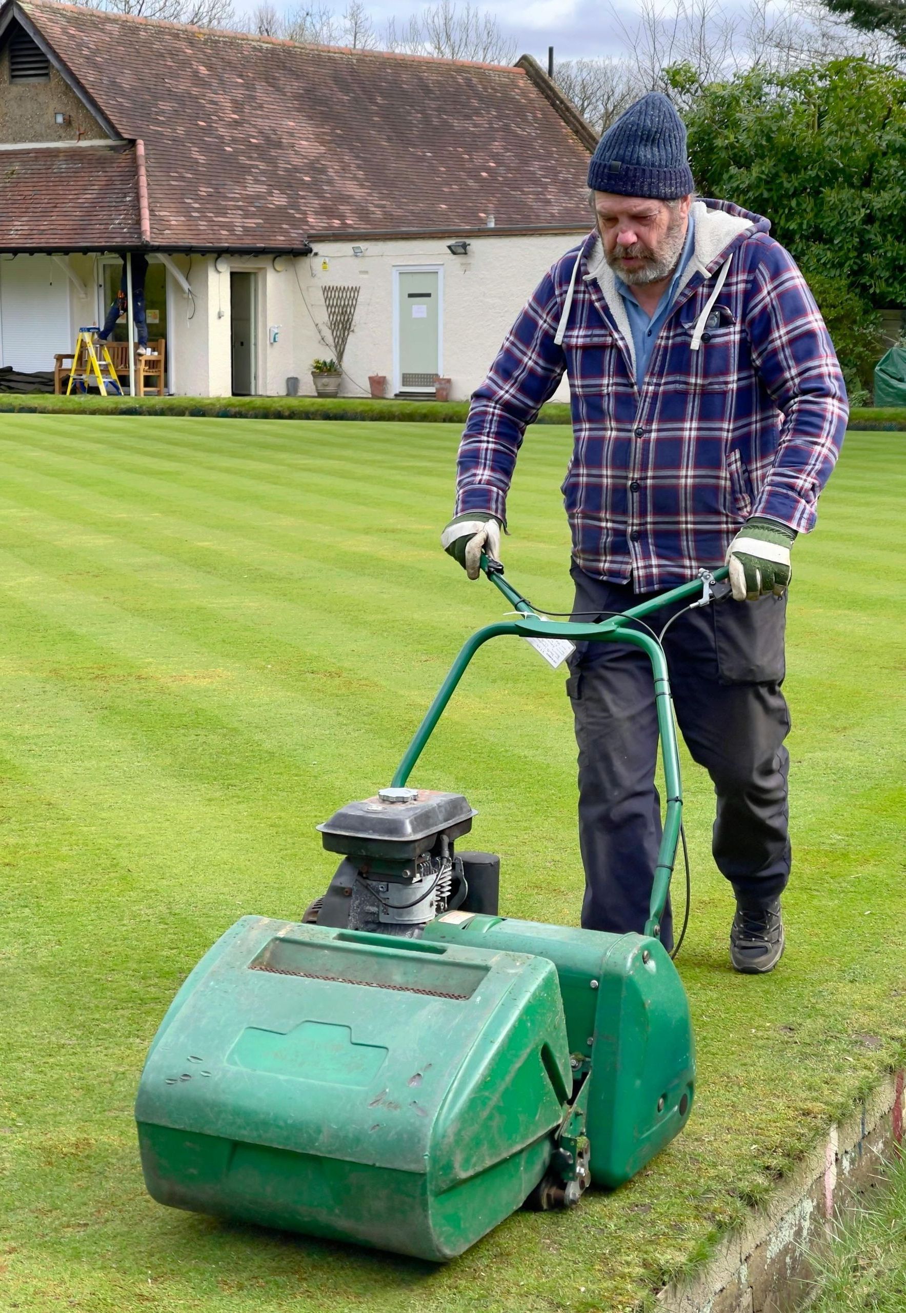 A man is mowing a lush green lawn with a lawn mower.