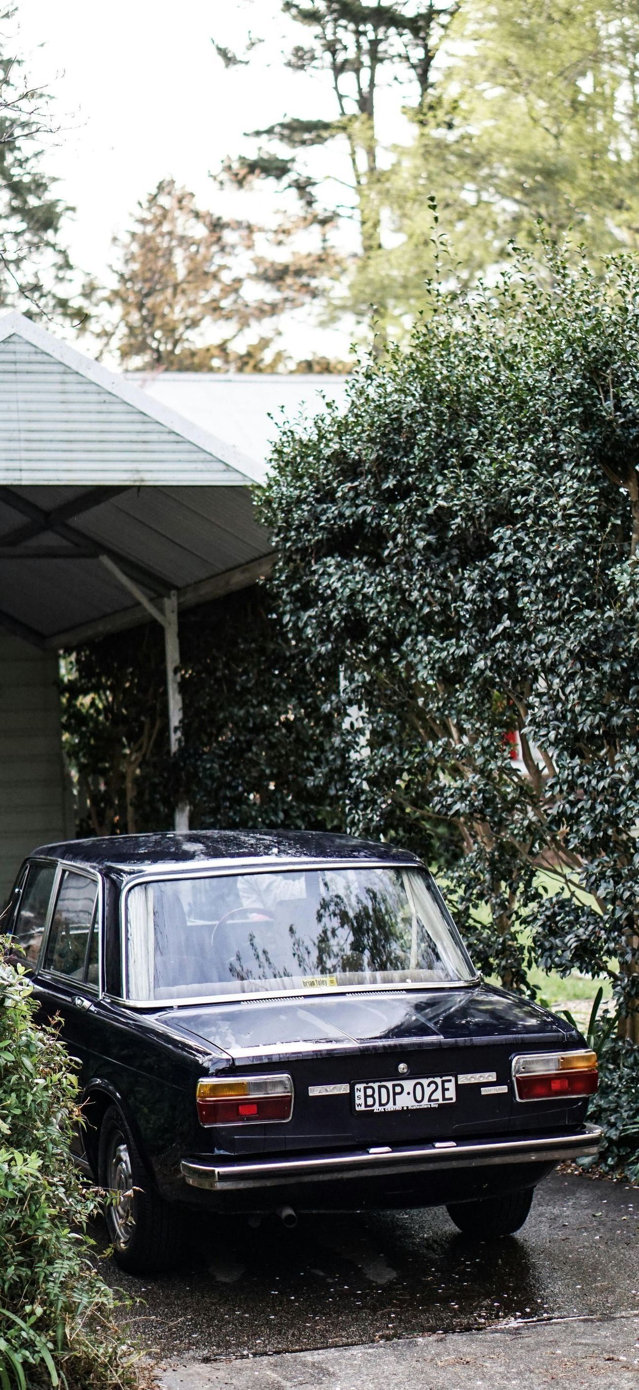 A black car is parked in front of a house.