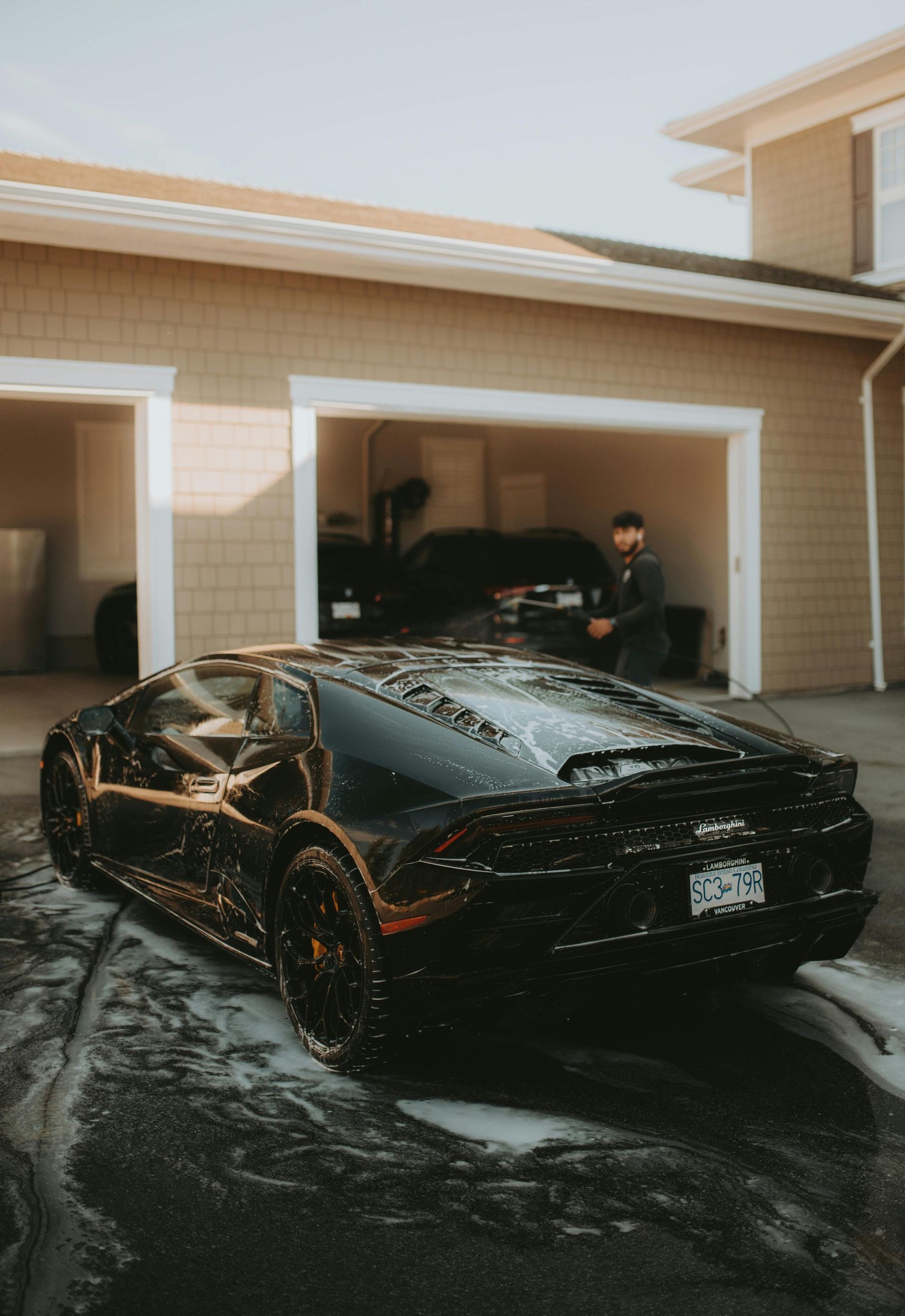 A black sports car is parked in front of a garage.