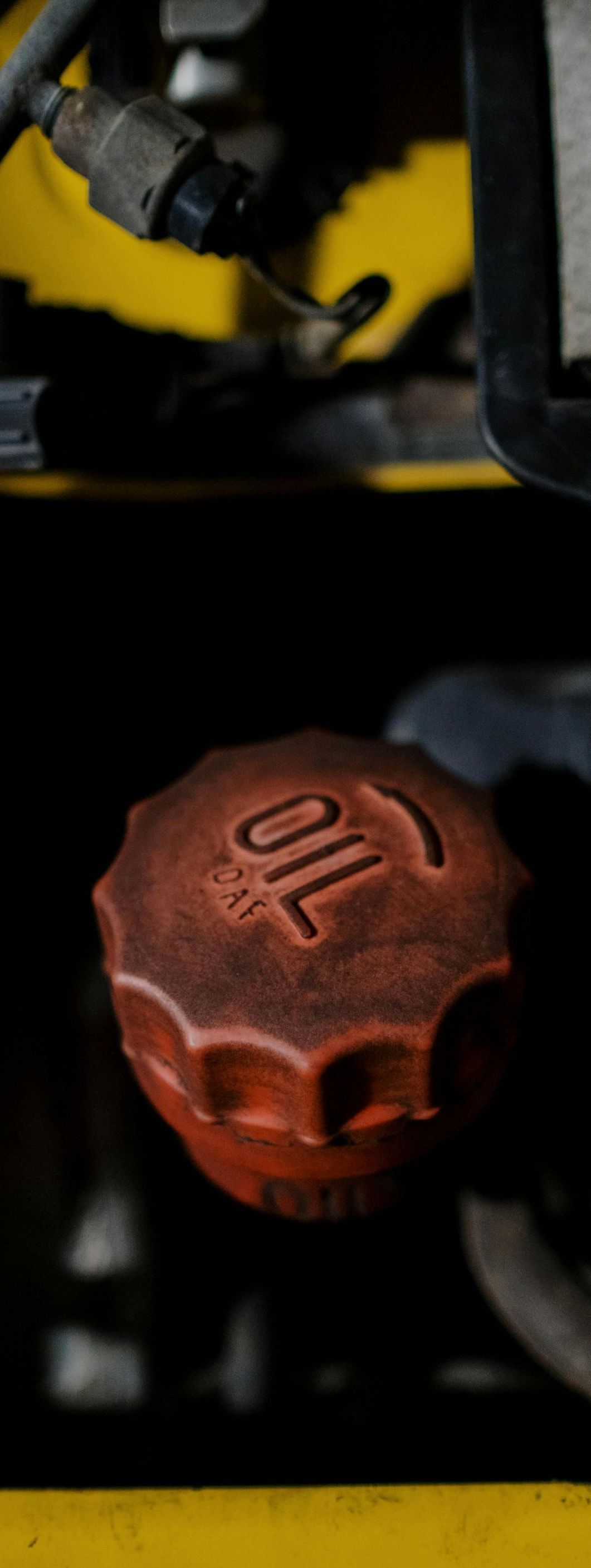 A close up of a red oil cap on a yellow car.