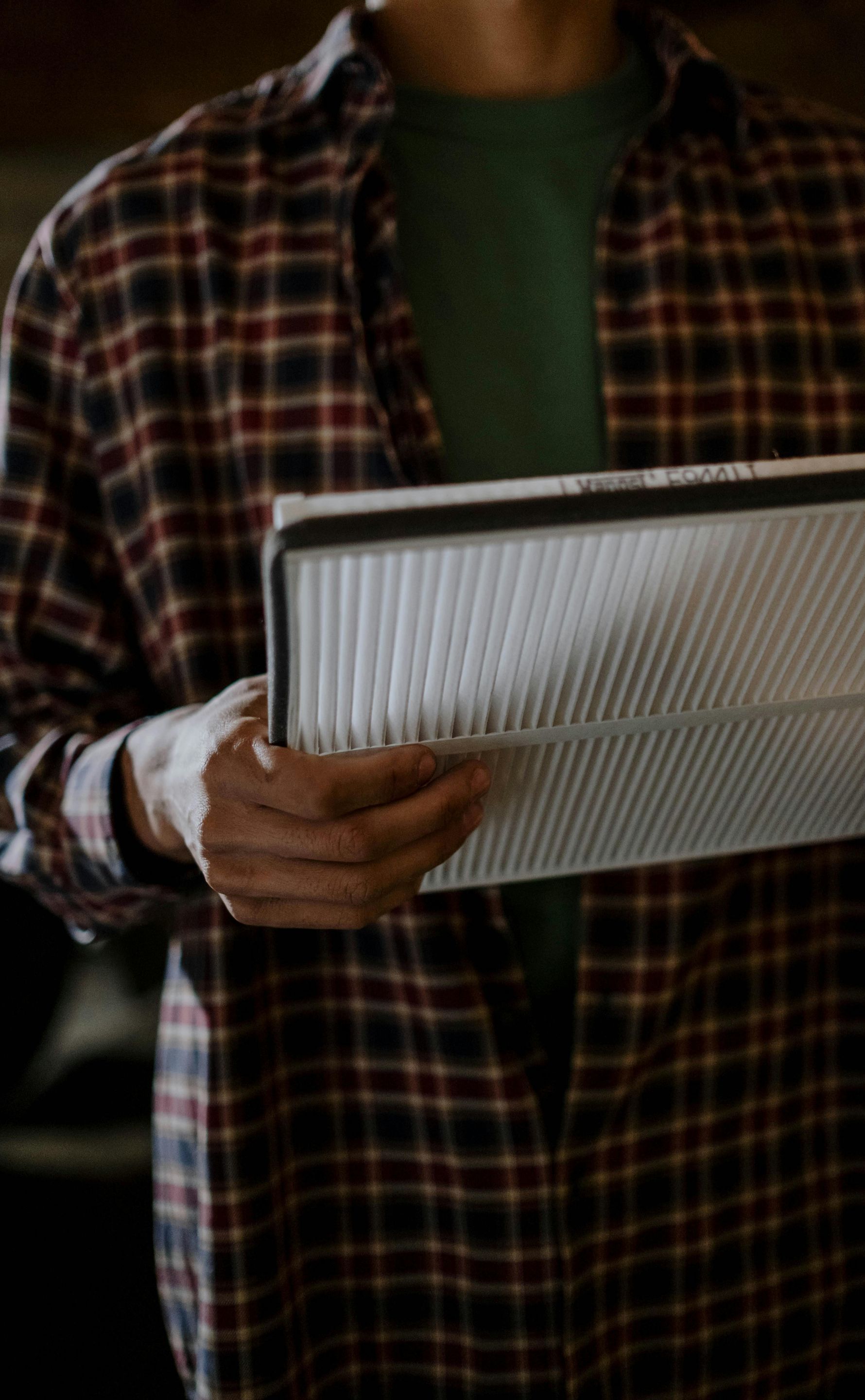 A man in a plaid shirt is holding a piece of paper in his hands.