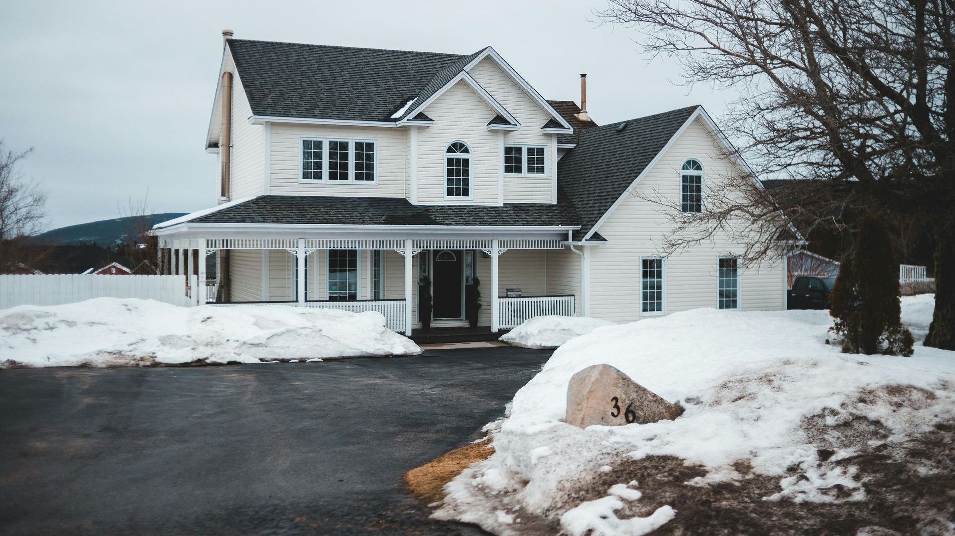 A white house with a black roof is surrounded by snow.